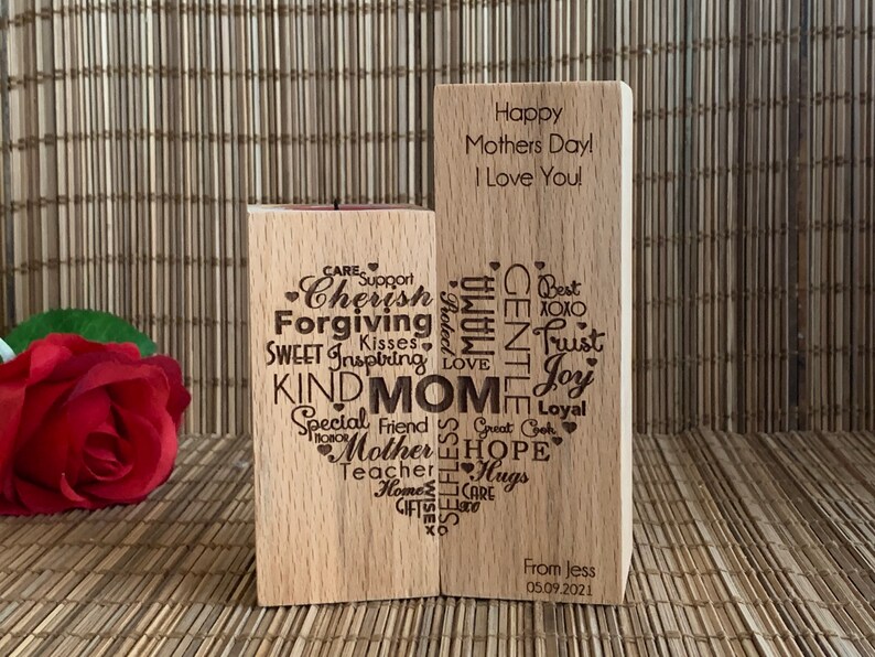 May include: Two wooden blocks with engraved messages. The left block has a heart shape with words like "Cherish", "Forgiving", "Kind", and "Mom" inside. The right block has the message "Happy Mothers Day! I Love You!" and a signature "From Jess 05.09.2021".