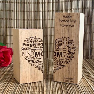 May include: Two wooden blocks with engraved messages. The first block has a candle holder and is engraved with words like "Cherish", "Forgiving", "Kind", and "Mother". The second block is engraved with "Happy Mothers Day! I Love You!" and a list of words like "Trust", "Joy", and "Hope".