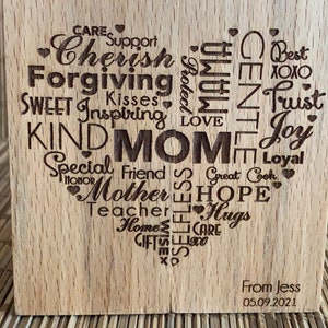 May include: Wooden heart-shaped plaque with the word "MOM" in the center surrounded by words describing a mother's qualities, such as "Cherish", "Forgiving", "Kind", "Special Friend", "Hope", "Love", "Trust", "Joy", and "Hugs". The plaque also includes the text "From Jess 05.09.2021".