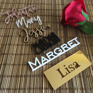 May include: A set of six personalised name place cards in various colours and fonts. The names are "Jonathan", "Mary", "Jessica", "Maria", "Margaret", and "Lisa".