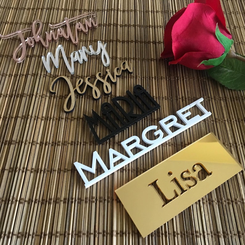 May include: A set of six personalised name place cards in various colours and fonts. The names are "Jonathan", "Mary", "Jessica", "Maria", "Margaret", and "Lisa".