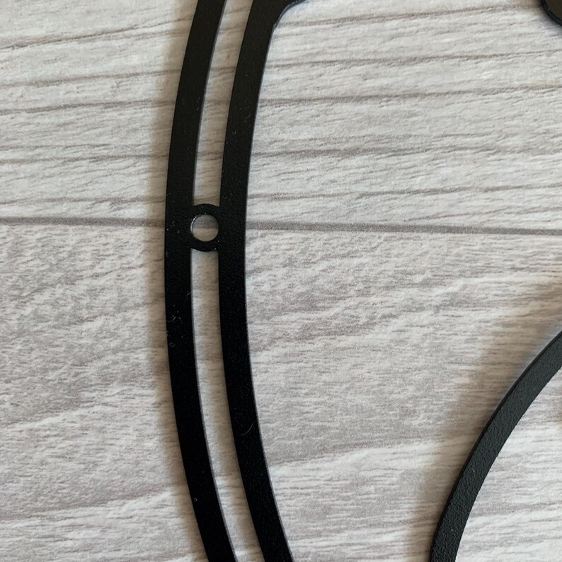 May include: Black metal wall decor in the shape of a yin yang symbol. The symbol is made of two overlapping circles, one black and one white.