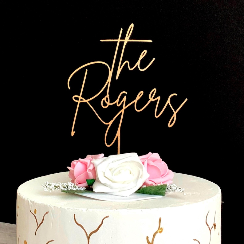 Personalized cake topper placed on a beautifully decorated wedding cake, displaying “Mr & Mrs” with the couple’s last name in an elegant handwritten font.