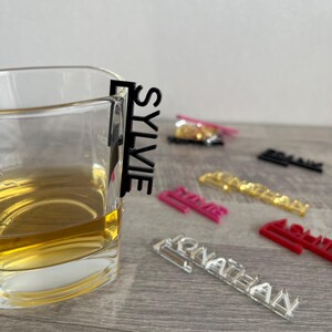 A set of black acrylic drink markers with names written on them. The names include "Sylvie", "Frank", "Jonathan", "Ashley", and "Julie".