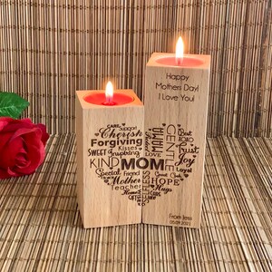 May include: Two wooden candle holders with a heart-shaped design. The left holder has words like "Cherish", "Forgiving", "Kind Mom", and "Special Friend" engraved on it. The right holder has the text "Happy Mothers Day I Love You" engraved on it. The candle holders are on a woven bamboo surface.