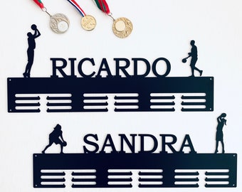 May include: Black metal medal display rack with two rows of slots for medals. The top row has the name "RICARDO" and a basketball player silhouette. The bottom row has the name "SANDRA" and a basketball player silhouette.