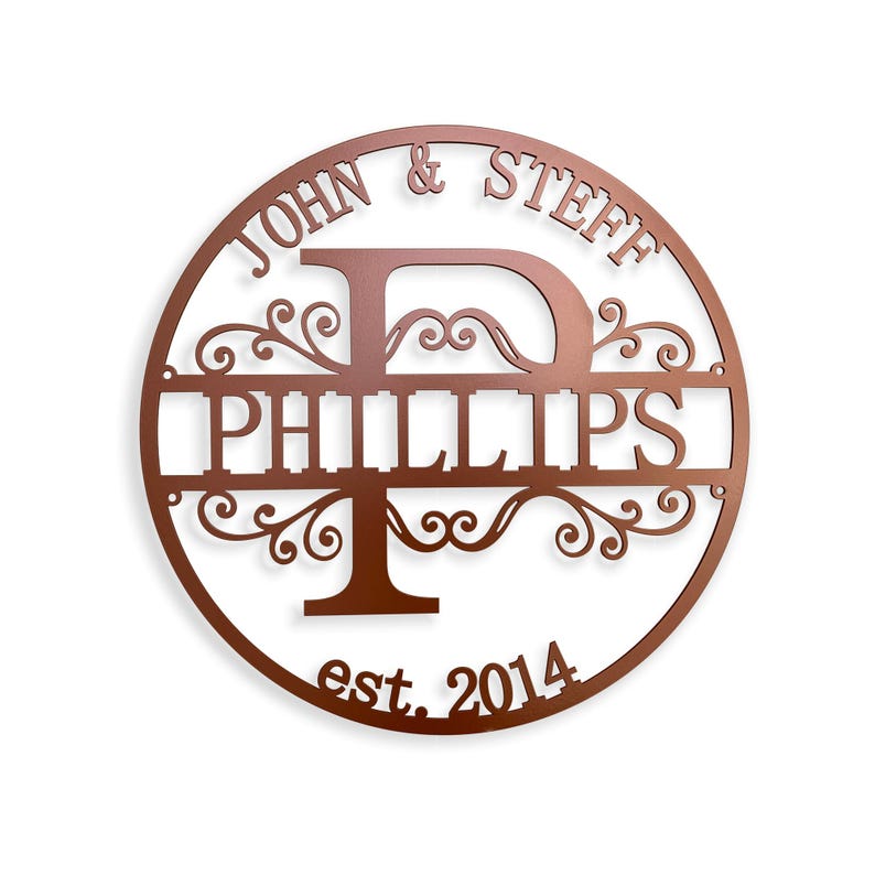 May include: A copper-colored, circular metal sign with the names "JOHN & STEFF" at the top and "PHILLIPS" in the center. The letter "D" and "T" are incorporated into the design, with decorative flourishes. The text "est. 2014" is at the bottom.