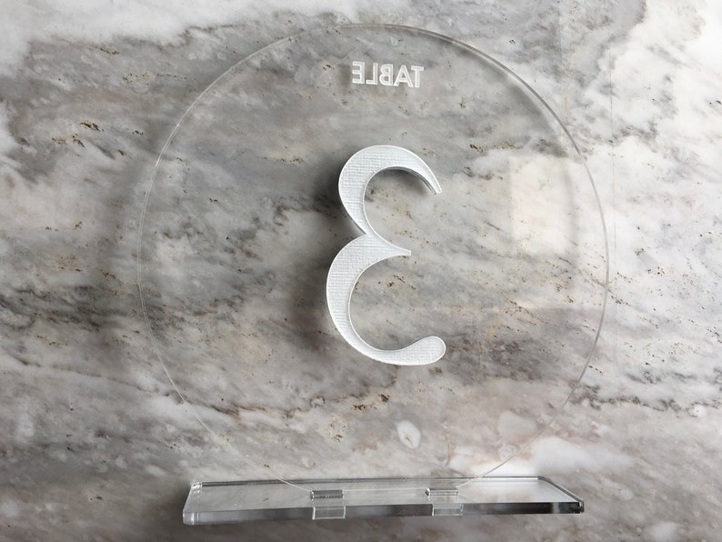 May include: Clear acrylic table number with the number 3 printed in white. The text "TABLE" is printed upside down at the top of the circle.
