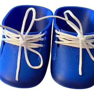 May include: A pair of bright blue toy shoes with white laces. The shoes are made of a solid material and have a classic lace-up design. The laces are tied in a bow.