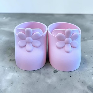 Peut inclure: Une paire de contenants cylindriques rose clair et lisses, chacun arborant un motif de fleur en relief sur le devant. Les objets présentent une finition mate, une forme arrondie simple, un dessus ouvert et une couleur unie et uniforme.