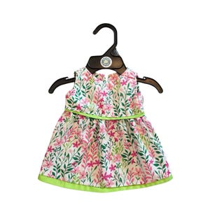 May include: A sleeveless dress with a floral pattern of pink flowers and green leaves on a white background. The dress has a lime green trim and is hanging on a black hanger.