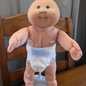 Boneco Cabbage Patch Kid dos anos 80, bebê prematuro careca, olhos verdes, covinha na fralda, fofo.