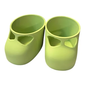Peut inclure: Deux objets cylindriques vert citron avec un dessus arrondi et une découpe sur le devant. Les objets ont une finition lisse et mate et semblent être en plastique. Les objets sont côte à côte.