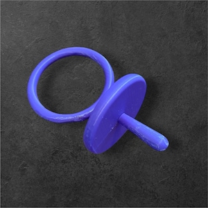 May include: A solid purple pacifier with a circular handle and a round, flat front. The pacifier is made of a smooth material and is set against a dark, textured background.