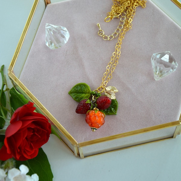 collier avec un pendentif en perles au chalumeau, d'une framboise et de deux fraises.