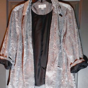 May include: A gray and black plaid blazer with black cuffs and a black interior. The blazer is hanging on a black hanger. The tag reads "ELLE".
