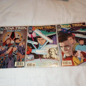 Puede incluir: Se muestran tres cómics de Star Trek, cada uno con una portada vibrante. Los cómics muestran personajes y escenas de la serie, con títulos y números de edición visibles. Las portadas presentan una variedad de colores e ilustraciones.