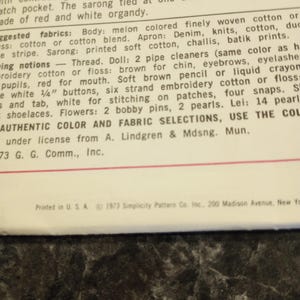 Może przedstawiać: Vintage strona z publikacji Simplicity Pattern Co. Inc. z 1973 roku. Tekst opisuje szmacianą lalkę z niebieską sukienką, fartuchem i sarongiem. Strona zawiera wyb&oacute;r tkanin i kolor&oacute;w.