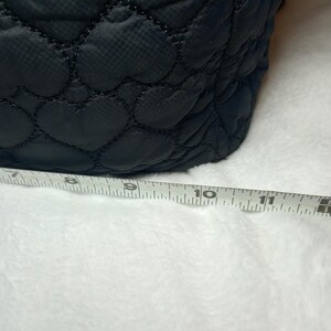 May include: Black quilted fabric with a heart pattern. The fabric is measured with a ruler, showing a length of approximately 10 inches.