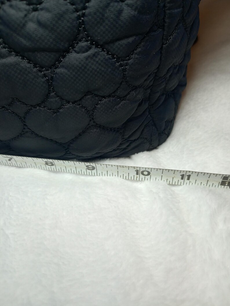 May include: Black quilted fabric with a heart pattern. The fabric is measured with a ruler, showing a length of approximately 10 inches.
