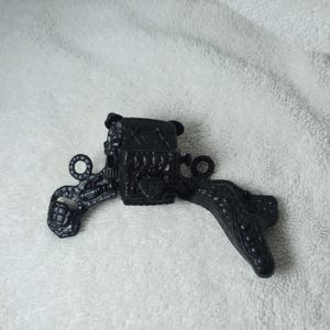 May include: A black, ornate, decorative object with a central rectangular component and two curved, wing-like extensions. The extensions feature intricate patterns and circular details. The object appears to be made of a solid, possibly metal, material.