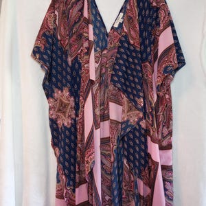 Può includere: Kimono con motivo paisley, scollo a V e maniche corte. La combinazione di colori comprende blu navy, rosa e bordeaux. Il tessuto sembra leggero. Il capo è disegnato con un davanti aperto. Il kimono è appeso a una gruccia nera.