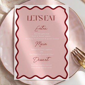 Op de afbeelding: Een roze menukaart met een rode rand en de tekst "LET'S EAT" in vetgedrukte, zwarte letters. Het menu bevat de opties "Entre", "Main" en "Dessert" met een verscheidenheid aan gerechten.