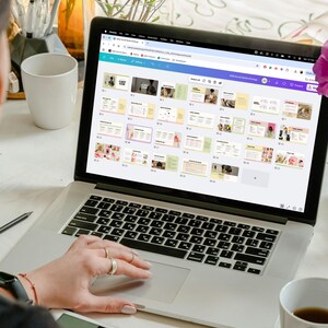 May include: A person using a laptop computer to view a presentation with multiple slides. The slides are colorful and feature text and images. The laptop is on a white table with a cup of coffee and a vase of flowers.