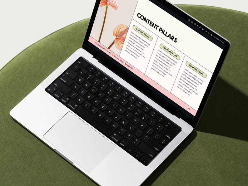 May include: A laptop computer open to a presentation slide titled "Content Pillars" with three sections labeled "Content Pillar". The laptop is on a green surface.