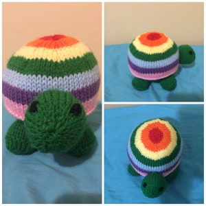 May include: A knitted rainbow turtle toy with a green shell and a colorful striped shell. The toy has a cute face with black eyes and a small mouth.