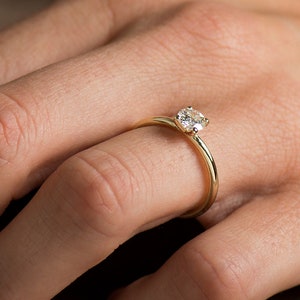 May include: A simple gold band ring with a single round diamond set in the center.