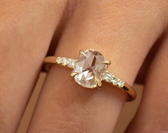May include: A gold ring with a large oval-shaped rose cut diamond and smaller diamonds set on the band.