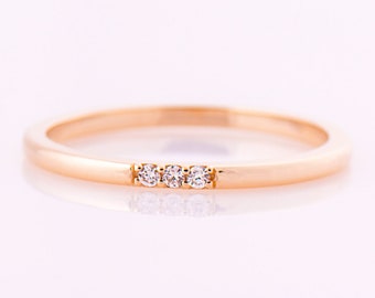 May include: A simple gold band ring with three small diamonds set in a row.