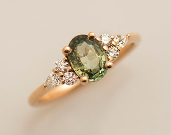 May include: A gold ring with a green oval gemstone surrounded by smaller white gemstones.