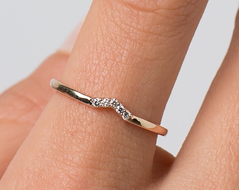 May include: A delicate gold band ring with a row of small diamonds set in a curved shape.