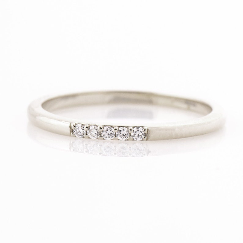 Op de afbeelding: Een dunne zilveren band met vijf kleine diamanten in een rij.