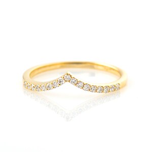 May include: A gold band ring with a chevron shaped row of small diamonds.