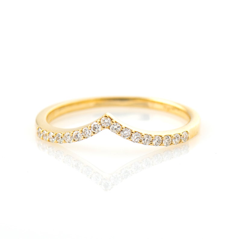 May include: A gold band ring with a chevron shaped row of small diamonds.