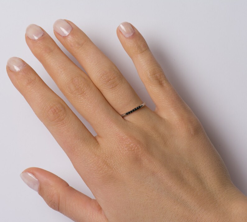 Peut inclure: Une d&eacute;licate bague en argent avec une rang&eacute;e de petits diamants noirs.