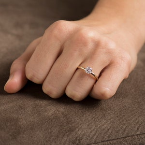 May include: A gold band ring with a single round diamond.