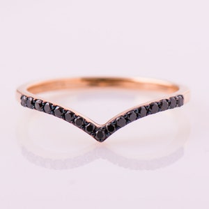 May include: A delicate gold ring with a V-shaped band of black diamonds.