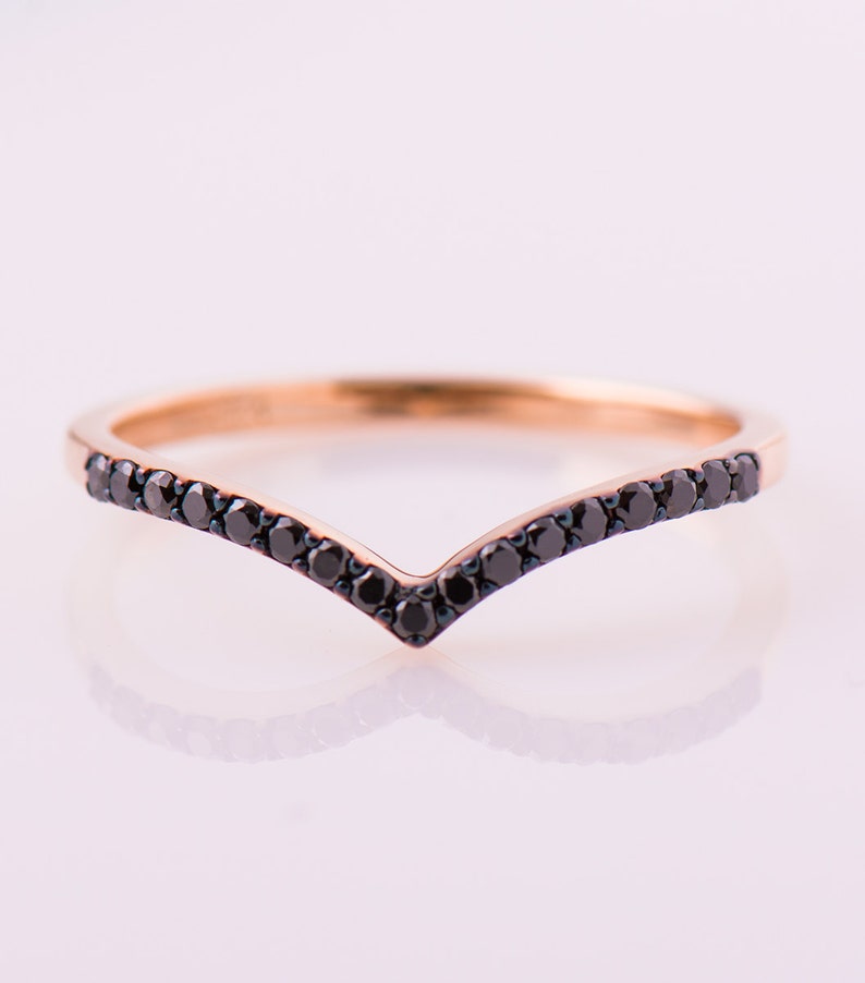 May include: A delicate gold ring with a V-shaped band of black diamonds.