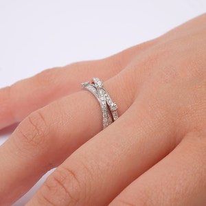 May include: A silver ring with multiple bands set with small diamonds. The ring is worn on a person's finger.