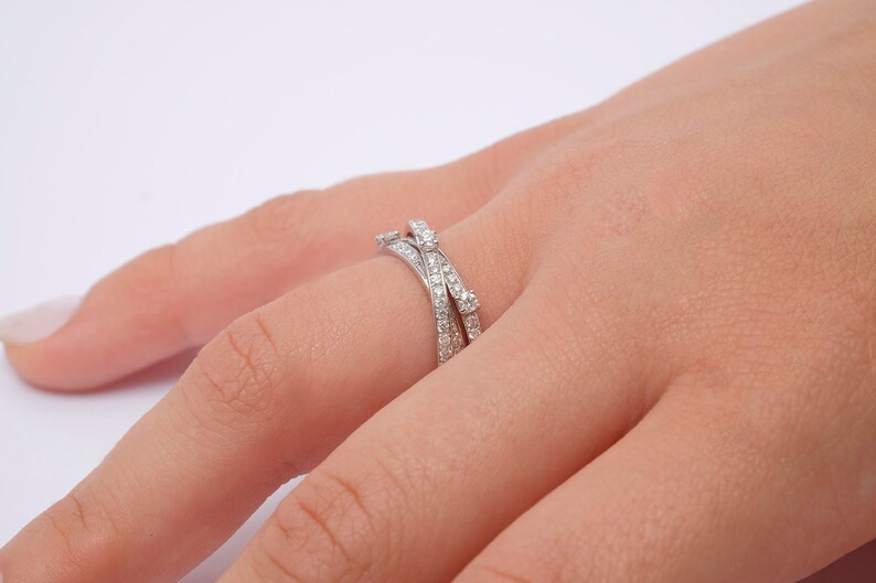 May include: A silver ring with multiple bands set with small diamonds. The ring is worn on a person's finger.