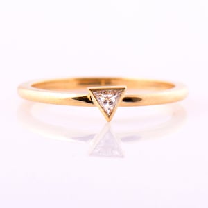 May include: A simple gold band ring with a small triangular diamond set in a triangular prong setting.