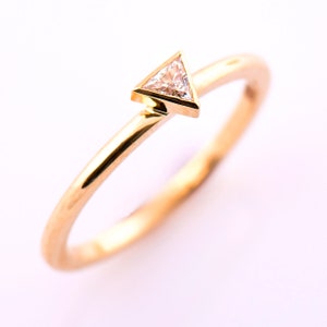 May include: A gold band ring with a small triangular diamond set in the center.