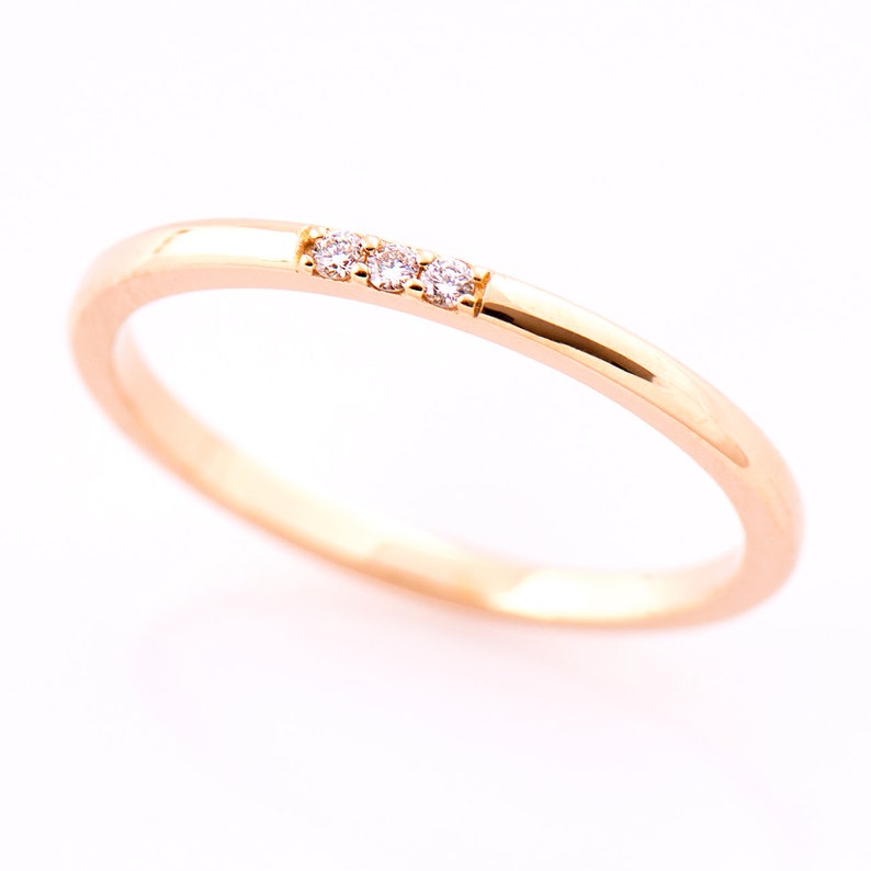 May include: A thin gold band ring with three small diamonds set in a row.
