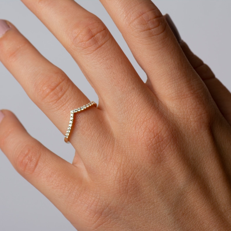 May include: A gold ring with a V-shaped band set with small diamonds.