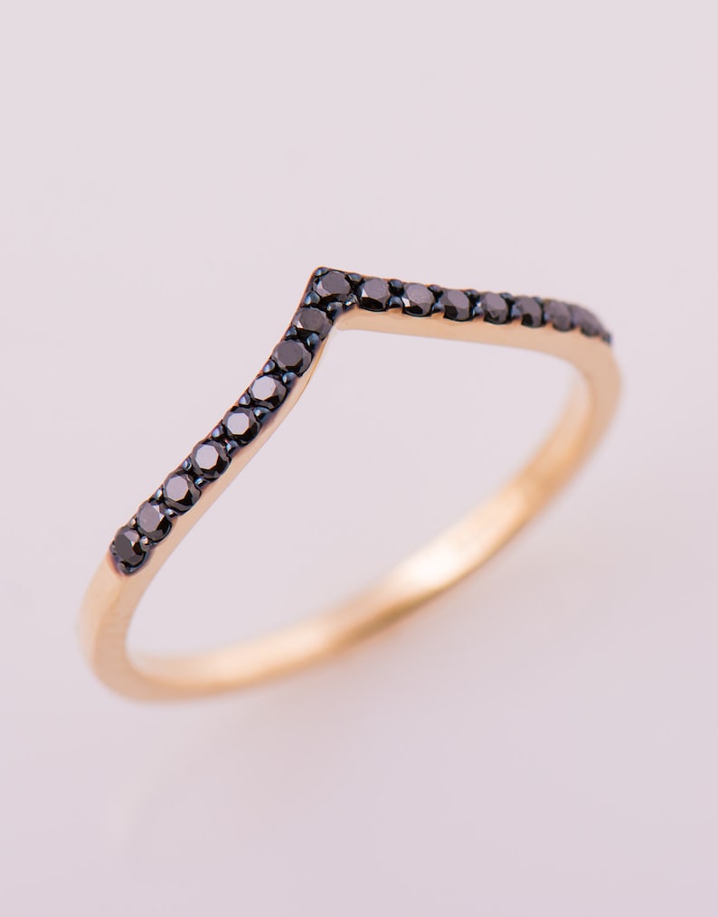 May include: A gold band ring with a row of black diamonds set in a V-shape.