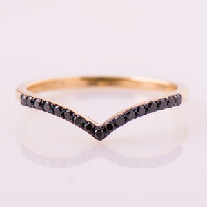 May include: A gold band ring with a V-shaped row of black diamonds.